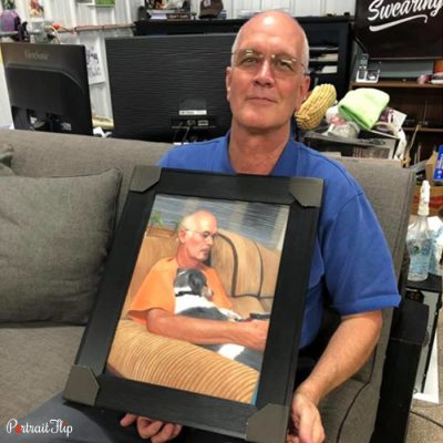 A man holding a frame in his hand that showcase vintage portraits of a man and a woman